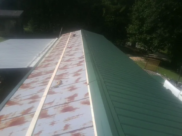 Old rusted panels beside newly installed green metal roofing — Wind Damage Roof Repair by Roofing Brothers in Lone Tree