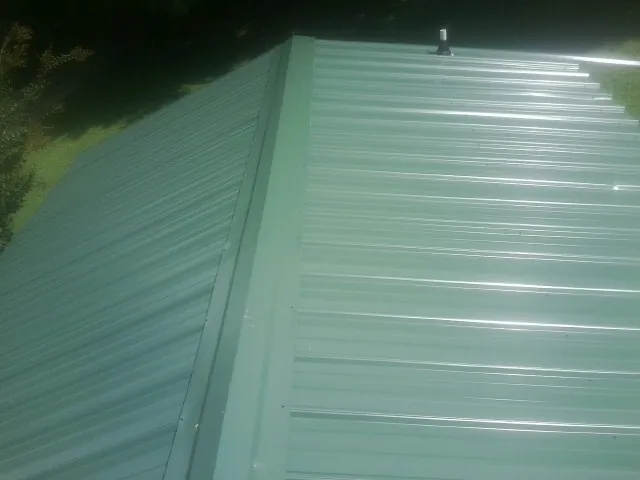 New green metal panels meeting at the ridge of a roof — Flat Roof Repair work by our crew in Lone Tree