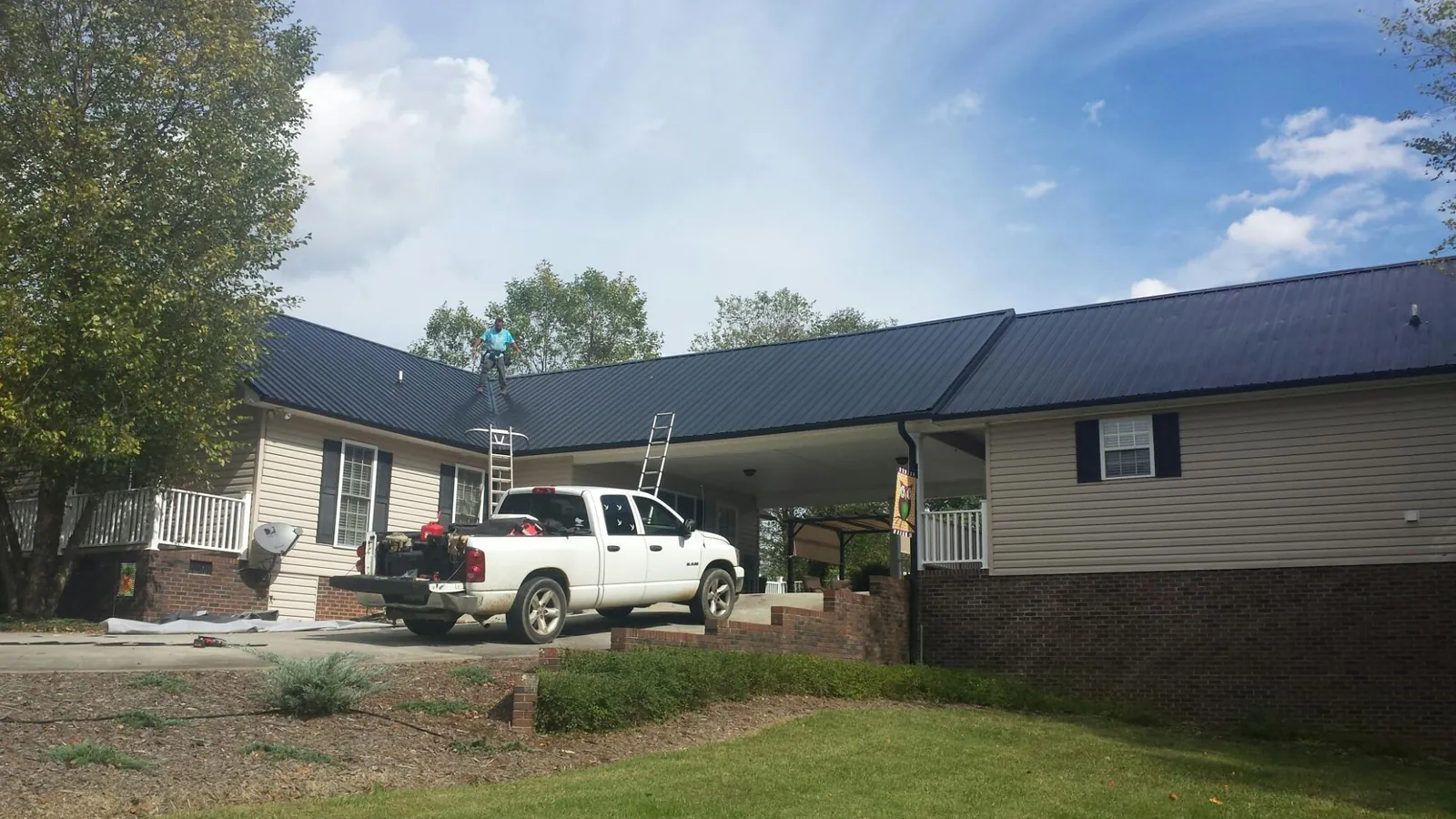 Black metal roof over a home and attached breezeway with ladders set in Lone Tree