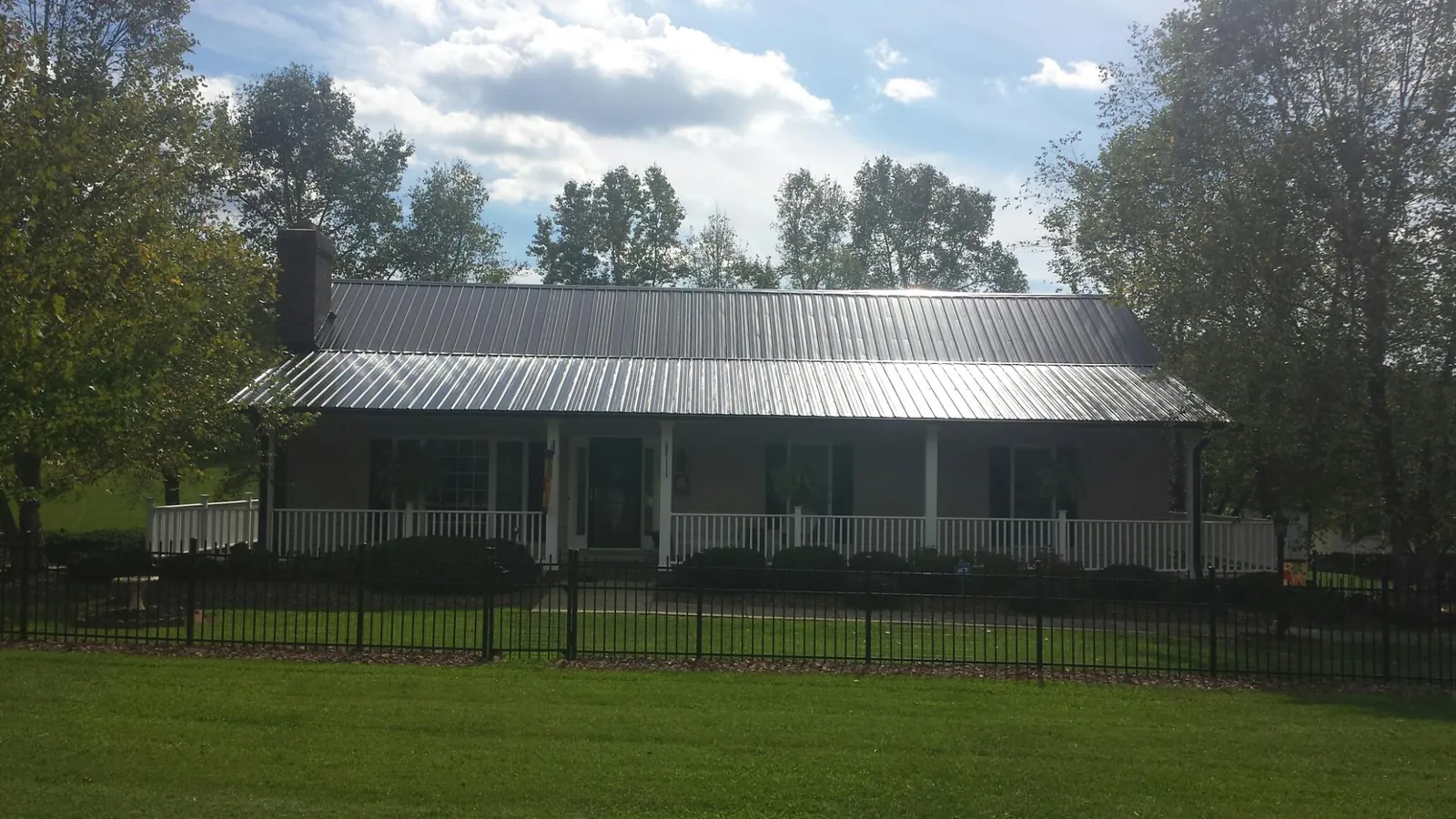 Gray metal roof on a brick ranch with a full width front porch — Gutter Guard Installation work by our crew in Lone Tree
