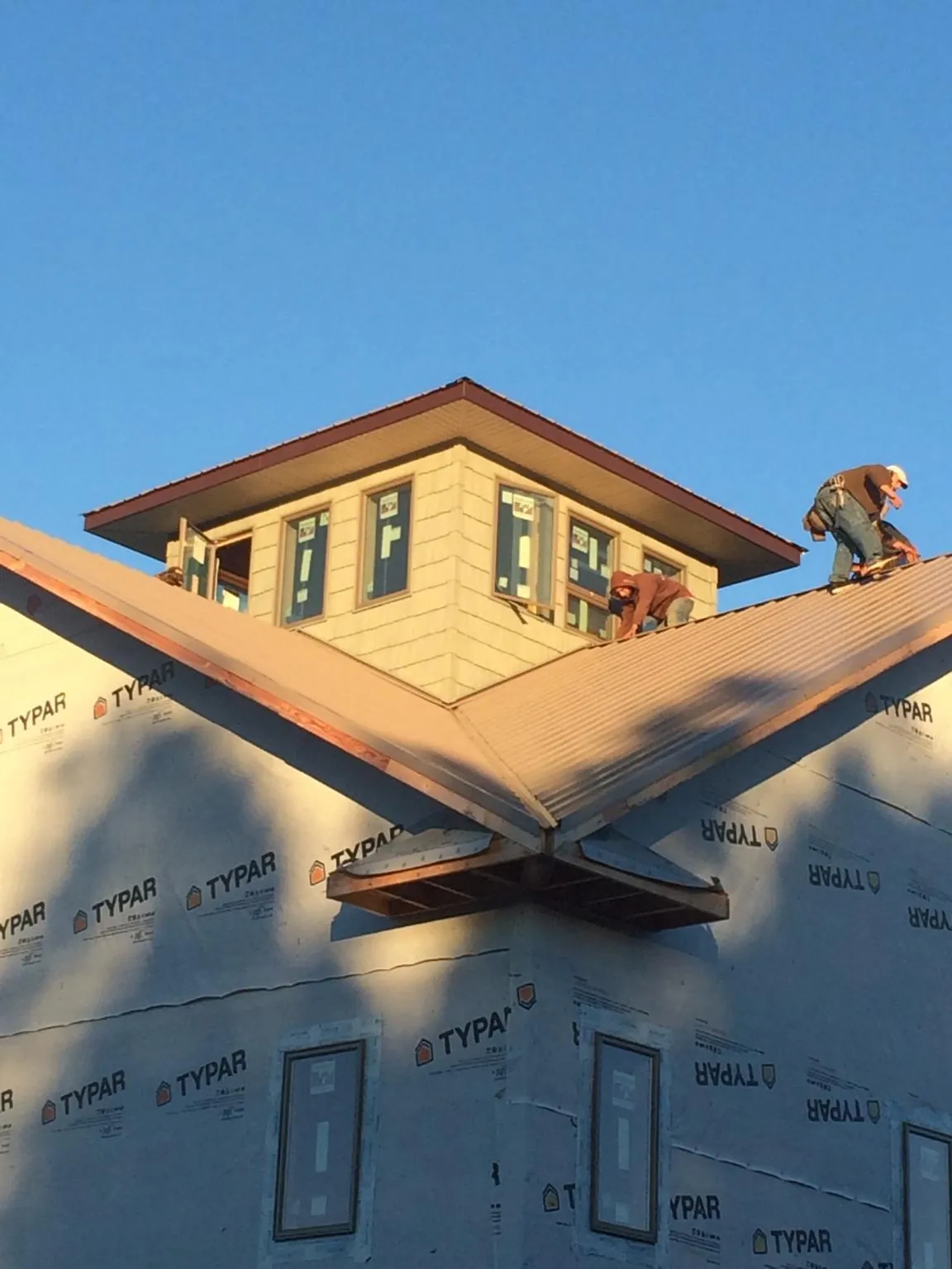 Roofers working around a rooftop cupola on a new metal roof at sunset — Roof Waterproofing in Lone Tree by Roofing Brothers